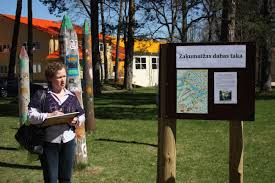 Dabas takas atklāšanas brīdī skolas tuvumā skolotāja Ināra Kleinberga stāsta par dabas taku un iepazīstina ar Dabas takas informācijas stendu.