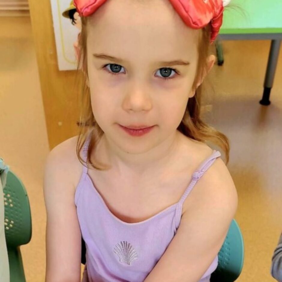 Jauna meitene ar rozā miega masku uz pieres, uz kuras rakstīts 