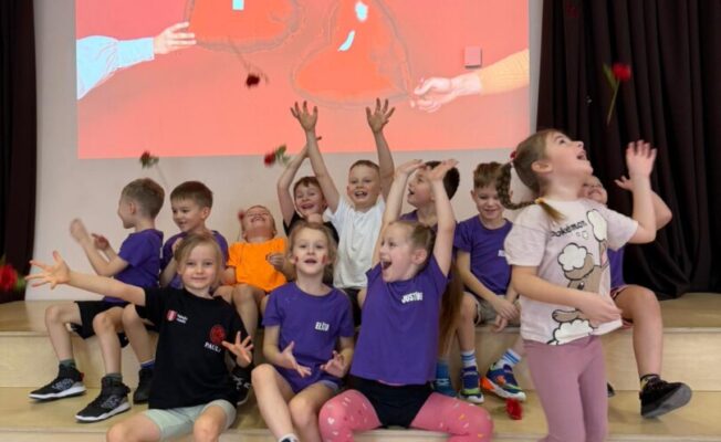 Priecīgi bērni, rozes. Fonā ekrāns ar sirdīm.