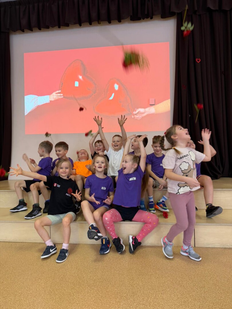 Priecīgi bērni, rozes. Fonā ekrāns ar sirdīm.